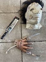 Overview of lot showing Michael Myers mask, chef knife in packaging, Freddy Krueger glove