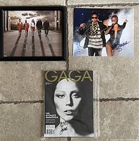 Overview photo showing all four items: framed signed Breaking Bad photo, signed Jay Z & Beyoncé photo, Gaga 2017 signed magazine, and sealed Gaga collector's edition magazine.