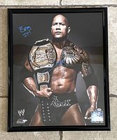Framed 16x20 photo of Dwayne “The Rock” Johnson wearing WWE Championship belt, signed in blue marker with “Bring it!” inscription