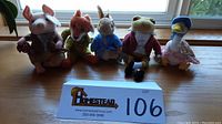Lot of five Beatrix Potter Beanie Babies lined up side by side on a wooden surface with a window background. Includes Jemima Puddle-Duck, Jeremy Fisher, Peter Rabbit, Mr. Tod, and Pigling Bland.