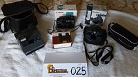Full lot overview including all cameras and binoculars with their boxes and cases laid out on a surface.