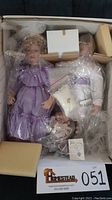 Full view of both Matthew and Melanie bisque porcelain dolls inside original box with packaging and accessories.