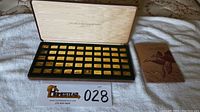 Full overview of open display case containing 50 gold plated plaques arranged in rows