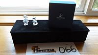 Two clear Swarovski Kris Bear crystal figurines, bride and groom, placed on black fabric with the original navy blue Swarovski box behind them.