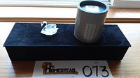 Full view of the Swarovski crystal swan figurine with its original cylindrical box on a black velvet display.