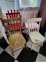 Four children's wooden chairs arranged together showing various finishes and wear.