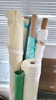 Photo of multiple fabric rolls standing upright, showing beige cotton flannel, light blue bamboo velour, white bamboo flannel, and green felt fabric.