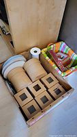Photo of kraft paper boxes, decorative fabric baskets, and a roll of paper towel in a wooden crate