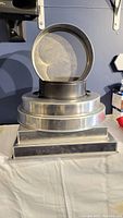 Large stack of professionally sized round and rectangular cake pans and cake boards on a table.