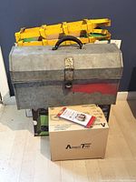 Vintage metal toolbox with handle and latch, surface wear visible