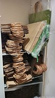Shelves stocked with stacks of new brown and green paper shopping bags with twisted paper handles, some wrapped in plastic packaging.
