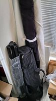 Photo showing two long rolled fabric backdrops in black and white leaning against the wall with carrying bag and stands nearby.