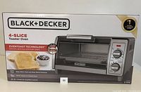 Front view of sealed boxed Black & Decker 4-slice toaster oven showing model and EventToast technology branding.