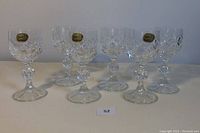 Front angled view of all six crystal liqueur glasses arranged in two rows showing details and heights, with three glasses bearing original labels visible.