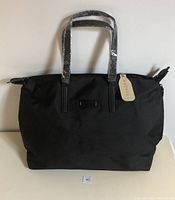 Front view of the black nylon tote bag with plastic-draped handles and Bugatti logo tag.