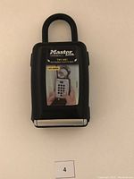 Front view of black MasterLock portable push button lock box with visible combination buttons and shackle lock.