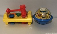 Photo of vintage Fisher Price Tap and Turn Toolbench toy with hammer and Roly Poly Floor Chime Ball toy side by side on a flat surface.
