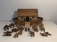 Front view of wooden Noah's Ark with all wooden animal and human figures arranged in front of it.