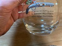 Close-up of a glass showing illustration and text of a percussion duelling pistol by Robinson 1857 from the Adams Antique Gun Collection series.