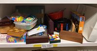 Shelf with multiple board games and puzzles including wooden game sets and plastic bags with game pieces