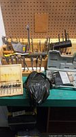 Overview of drill bits, files, and rotary tool bits arranged in wooden block organizer and cases