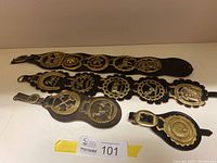 Four horse halter decorative pieces displayed on white surface showing brass medallions and leather backing