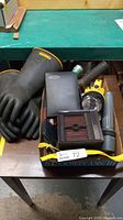 Photo showing the black electrical safety gloves, small space heater, Buffalo wire strippers, flashlights, and multimeter items.