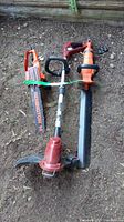 Three corded electric yard tools laid out on ground: Toro grass trimmer, Black&Decker hedge trimmer, and Remington chainsaw