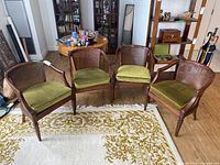 Four wooden armchairs arranged on a white rug with a floral pattern, showing front and back views of the chairs.