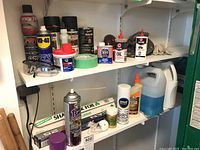 Shelf with aluminum foil rolls, adhesive tape, glue bottles, and liquid containers including large jugs and spray cans.