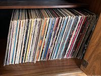 Shelf of vertically stacked vinyl LP records in paper sleeves
