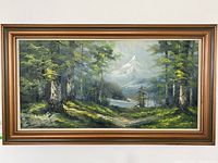 Framed landscape painting showing a forest and mountain scene with a wide wooden frame.