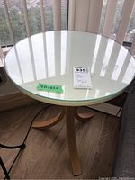 Side table with round clear glass top and wood laminate base with curved legs, showing approximate dimensions 18x18x22 inches