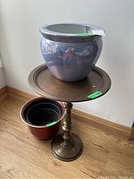 Metal pedestal side table with two plant pots on and beside it