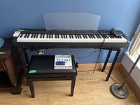 Full view of piano on stand with bench and instruction book