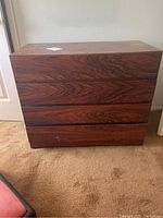 Front view of the four drawer dresser showing the wood grain finish and some surface marks.