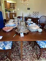Wood dining table shown with dishes and decanters on top to display scale and surface condition. Dining room setting visible.