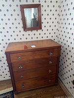 Full view of mid-toned wood dresser with coordinating wall mirror in room
