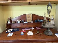 Wide view of the top of the wooden cabinet showing multiple small decor items including oil server set, nativity scene, rosaries, plaque, decor bowls, toothpick holders, and money clip.