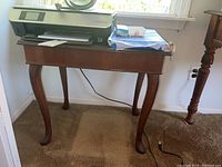 Vintage Queen Anne style end table with cabriole legs seen from side with HP Envy printer and accessories on top.