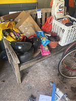 Wooden garden bench and contents including helmets, garden supplies, potting mix, and milk crate with Roundup and cleaning products