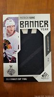 Front of the Patrick Kane Banner Year hockey card with a piece of dark fabric embedded and player image.