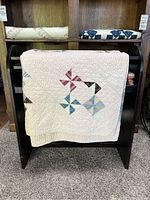 Front view of the antique quilt draped showing pinwheel patchwork and fabric condition.