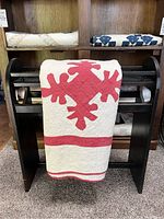 Quilt draped over wooden rack showing full acorn motif and overall condition