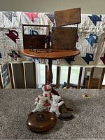 Maple 3-leg table with various collectibles placed on and around it, including wooden boxes, quilt bears, candle holder, bed warmer, and sad irons, against backdrop of a quilt
