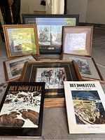 Overview of six framed prints arranged on floor with two books in front