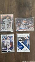 Four Aaron Judge baseball cards on wooden surface showing various designs and poses of the player in New York Yankees uniform.