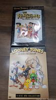 Both DVD collections side by side: The Flintstones Season 1 and Looney Tunes Golden Collection 4-disc set