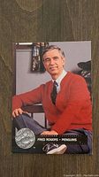 Front of Fred Rogers hockey card showing his photo in a red cardigan and black tie with silver Penguins logo and text "Fred Rogers - Penguins"