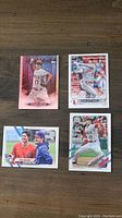 Front view of 4 Shohei Ohtani baseball cards laid out on wooden surface.